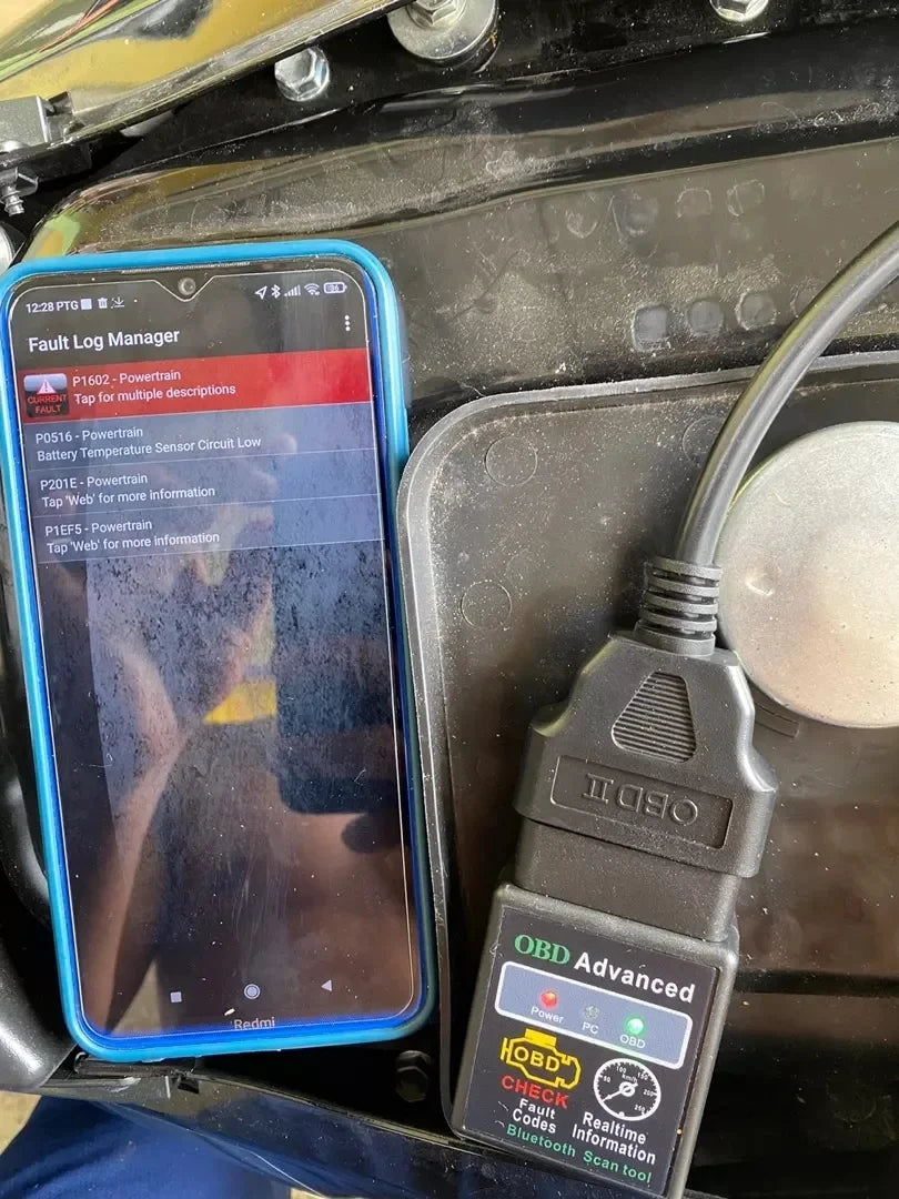OBD2 scanner plugged into a car with live data on a phone